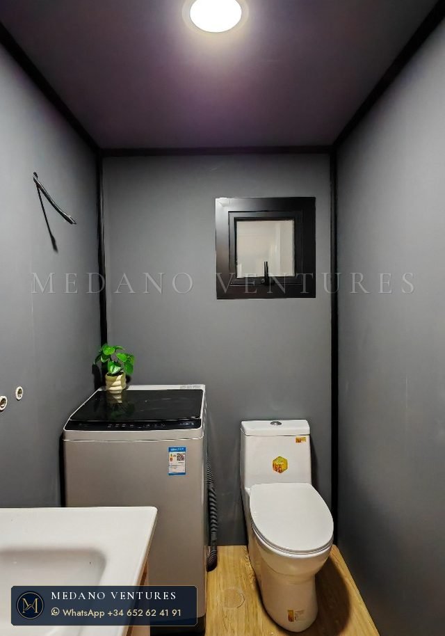 Baño en tonos oscuros con espacio para lavadora